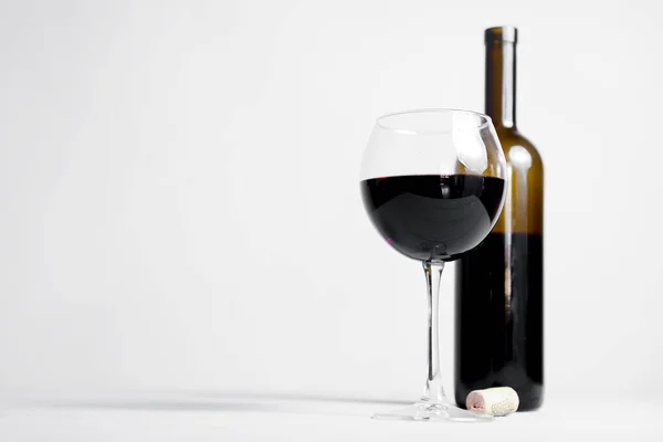 Red wine bottle without a label and glass filled iwth red wine. Over white background. Copy space banner. Wine concept.