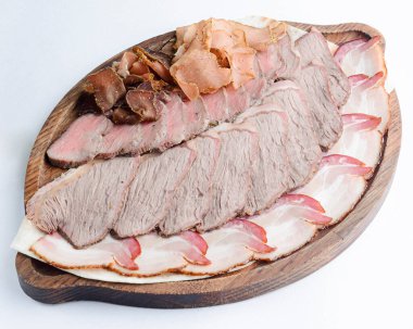 Beyaz arka planda tahta bir tahtada servis edilen farklı et ve sosislerden oluşan et tabağı. Gürcistan mutfağı, lezzetli carpaccio.