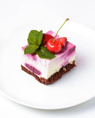 Beyaz arka planda beyaz bir tabakta servis edilen üzerinde krema ve taze kirazlı gül kirazlı cheesecake. Lezzetli tatlı zamanı, pastayı kapat, uzay afişini kopyala.