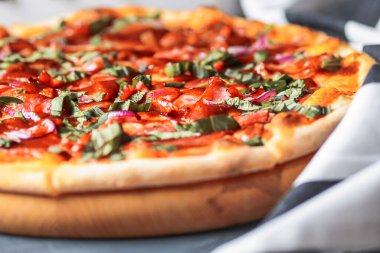 Domatesli İtalyan pizzası Prosciutto, şifalı otlar ve fesleğen siyah arka planda yuvarlak bir tahta üzerinde servis edilir. İtalyan mutfağı kavramı, modern pizza..