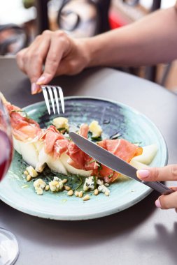 Restoranda jambon ve kavun salatası. Dışarıda İtalyan salatası yiyen genç bir kadın. İtalyan mutfağı kavramı.