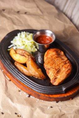 Kızarmış Rus patatesli ızgara tavuk fileto bifteği, yeşil salata ve domates sosu kırsal ahşap arka planda servis edilir. Akşam yemeği..