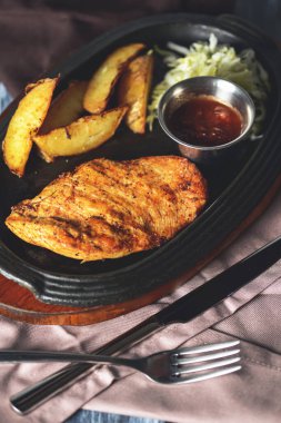 Kızarmış Rus patatesli ızgara tavuk fileto bifteği, yeşil salata ve domates sosu kırsal ahşap arka planda servis edilir. Akşam yemeği..