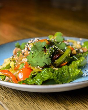 Mavi bir tabakta servis edilen taze sebzeli kuşkonmaz ve susam tohumlu salata karışımı. Öğlen ya da akşam yemeği fikri, sağlıklı yemek..