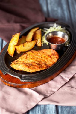 Kızarmış Rus patatesli ızgara tavuk fileto bifteği, yeşil salata ve domates sosu kırsal ahşap arka planda servis edilir. Akşam yemeği..