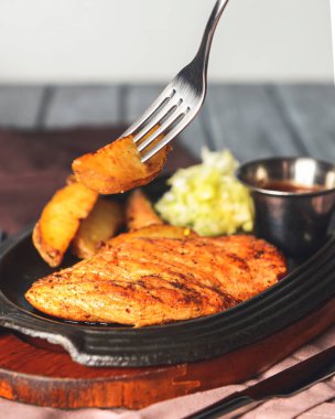 Kızarmış Rus patatesli ızgara tavuk fileto bifteği, yeşil salata ve domates sosu kırsal ahşap arka planda servis edilir. Akşam yemeği..