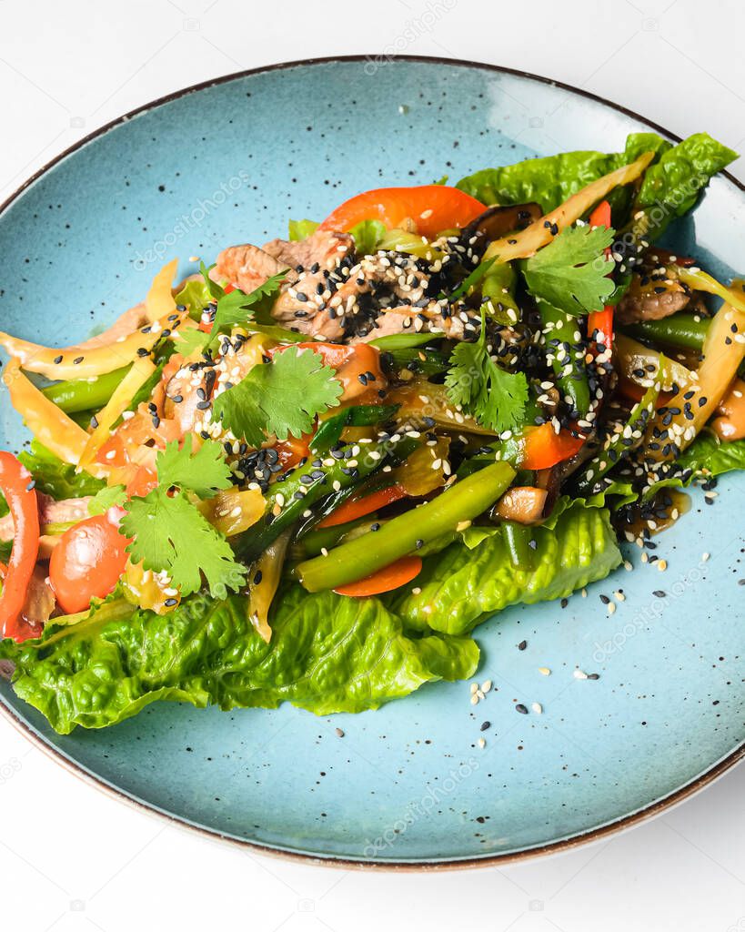 Salad mix with fresh vegetables asparagus and sesame seeds served on a blue plate. Lunch or dinner idea, healthy eating.