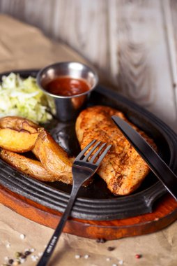 Kızarmış Rus patatesli ızgara tavuk fileto bifteği, yeşil salata ve domates sosu kırsal ahşap arka planda servis edilir. Akşam yemeği..