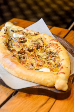 Restoranın içindeki ahşap bir tahtanın üzerinde servis edilen et ve mantarlı güzel açık khachapuri turtaları. Gürcistan mutfağı kavramı, geleneksel khachapuri tarifi.