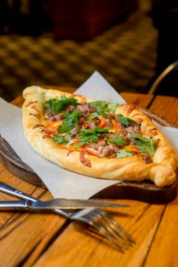 Restoranın içindeki ahşap bir tahtanın üzerinde servis edilen et ve mantarlı güzel açık khachapuri turtaları. Gürcistan mutfağı kavramı, geleneksel khachapuri tarifi.