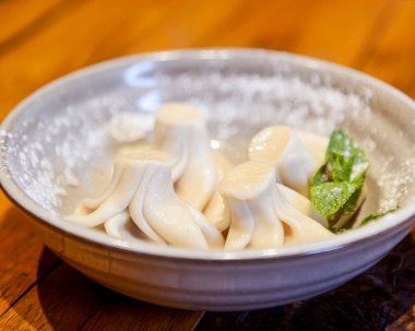 Khinkali ahşap masanın üzerinde seramik bir tabakta pişirildi. Gürcistan mutfağı kavramı, geleneksel khinkali tarifi.