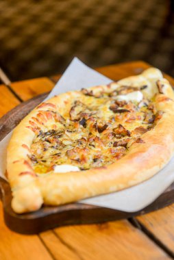 Restoranın içindeki ahşap bir tahtanın üzerinde servis edilen et ve mantarlı güzel açık khachapuri turtaları. Gürcistan mutfağı kavramı, geleneksel khachapuri tarifi.
