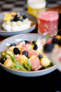 Kavun ve carpaccio ile taze salata, dut, meyve ve krem peynirli tatlı, bardakta meyve kokteyli. Yaz yemeği, dut yaz menüsü, İtalyan mutfağı. Siyah arkaplanda.