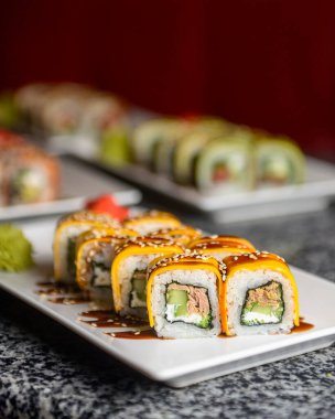 Philadelphia ya da California avokado ve krem peynirli suşi sarar. Peynirli suşi menüsü. Geleneksel Japon yemeği konsepti. Restoranda beyaz bir tabakta servis edilir, konsepti dışarıda yenir..