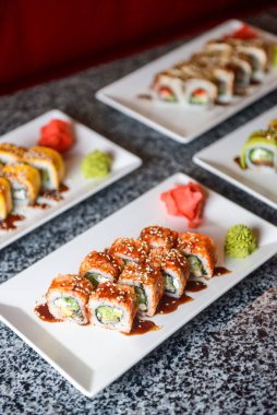 Avokado ve krem peynirli Philadelphia ya da California suşisi. Suşi menüsü. Geleneksel Japon yemeği konsepti. Restoranda beyaz bir tabakta servis edilir, konsepti dışarıda yenir..