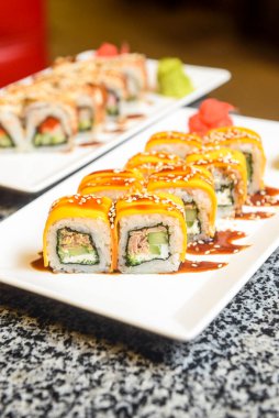 Philadelphia ya da California avokado ve krem peynirli suşi sarar. Peynirli suşi menüsü. Geleneksel Japon yemeği konsepti. Restoranda beyaz bir tabakta servis edilir, konsepti dışarıda yenir..