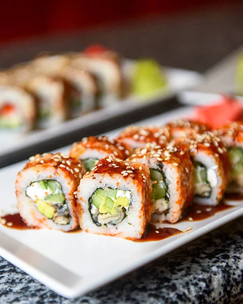 Avokado ve krem peynirli Philadelphia ya da California suşisi. Suşi menüsü. Geleneksel Japon yemeği konsepti. Restoranda beyaz bir tabakta servis edilir, konsepti dışarıda yenir..
