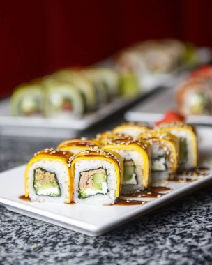 Philadelphia ya da California avokado ve krem peynirli suşi sarar. Peynirli suşi menüsü. Geleneksel Japon yemeği konsepti. Restoranda beyaz bir tabakta servis edilir, konsepti dışarıda yenir..