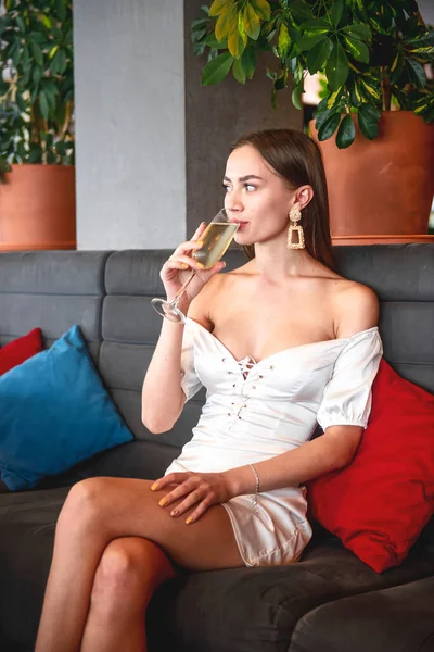 Beautiful sexy brunette woman in restaurant or cafe with ice cream tiramisu dessert. Fashion photo of young woman in black dress with hairstyle and makeup, eating dessert. Eat out concept.