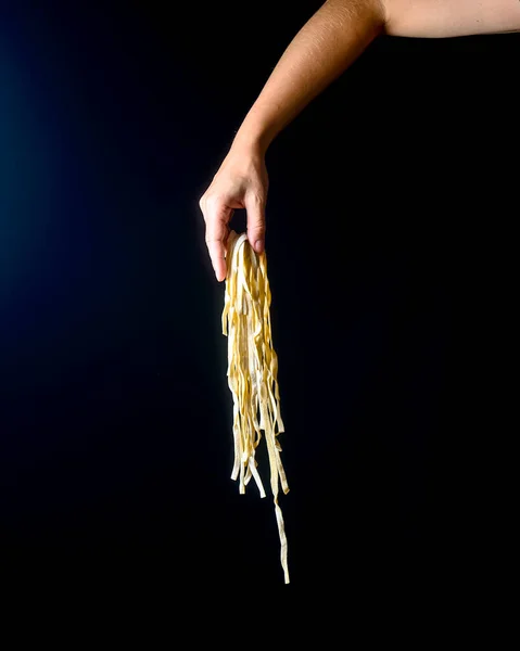 暗い背景に卵麺を投げる手 黒の上に手で調理されたパスタを飛んで 創造的な広告 イタリアのマカロニパスタ麺の広告コンセプト ストック写真