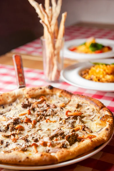 赤いテーブルクロスで木製のテーブルの上に白いプレートに提供キノコとピザを食欲をそそる イタリア料理のコンセプト 伝統的なピザレシピ — ストック写真