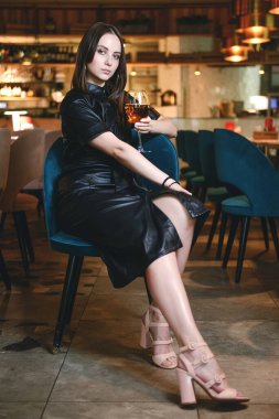 Bardakta şampanya içen ve gülümseyen genç bir kadının portresi. Restoranda boş zamanlarının tadını çıkarıyor. Kedi kulaklı siyah elbiseli kız..