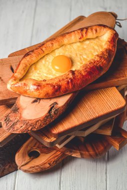 Yuvarlak ahşap bir tahtada servis edilen yumurtalı güzel açık khachapuri turtaları. Geleneksel Gürcistan mutfağı, khachapuri tarifi. Bir Khachapuri 'ye yaklaş..