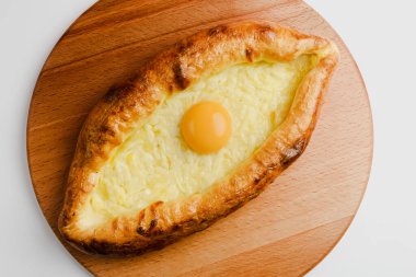 Yuvarlak ahşap bir tahtada servis edilen yumurtalı güzel açık khachapuri turtaları. Geleneksel Gürcistan mutfağı, khachapuri tarifi. Beyaz arkaplan.