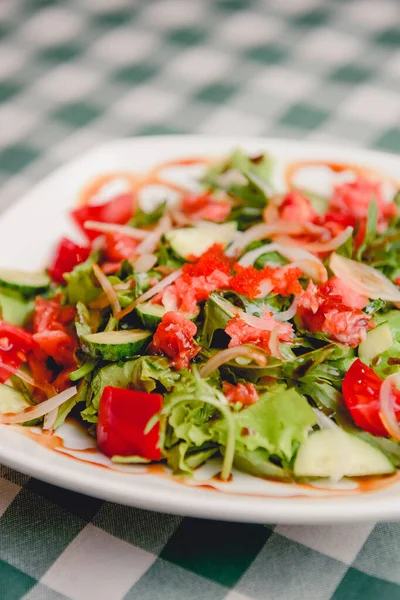 野菜イタリアのサラダに赤キャビアと新鮮なアルグラをトッピングし 緑のテーブルクロスの上に白いプレートで提供しています イタリア料理のコンセプト — ストック写真