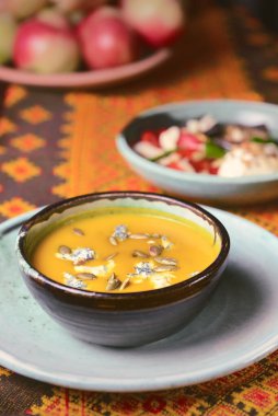 Ukrayna 'nın kırsal ahşap masasında servis edilen siyah bir kasede balkabağı çorbası. Sonbahar menüsü konsepti, Ukrayna mutfağı.