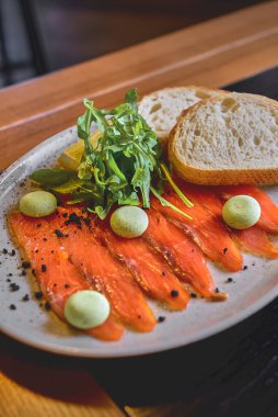 Siyah arkaplanlı ekmekle servis edilen somon balığı. Geçmişi bulanık, siyah masada servis edilmiş. Japon mutfağı kavramı.