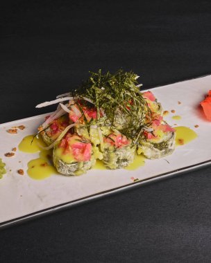 Somon, avokado ve nori soslu sıcak suşi. Lezzetli, iştah açıcı ve tuzlu suşi seti beyaz tabakta servis ediliyor. Japon mutfağı konsepti. Üst görünüm.