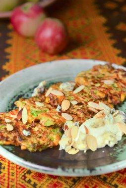 Kırsal ahşap bir masada geleneksel masa örtüsüyle seramik tabakta kızarmış patates krepleri. Ukrayna mutfağı kavramı.