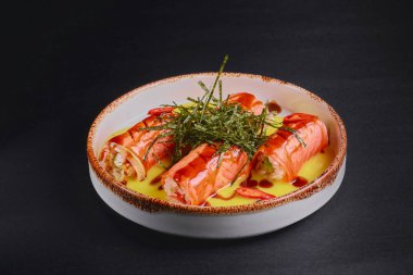 Siyah bir masada servis edilen krem peynirli füme somon ruloları ve bulanık bir arka plan. Japon mutfağı uygun..