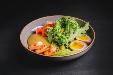 Haşlanmış yumurta, avokado, taze domates ve roka kaplı siyah bir tabakta hazır karides ya da karides. Sağlıklı beslenme konsepti, Japon mutfağı.