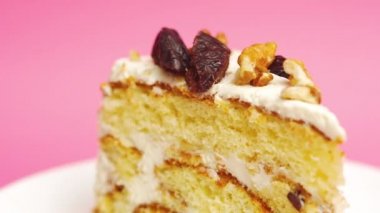 Pastel pembe arka planda bir dilim doğum günü pastası. Kremalı vanilyalı, beyaz bir tabakta. Pasta sunumu.