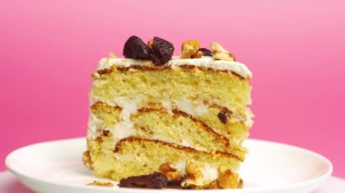 Pastel pembe arka planda bir dilim doğum günü pastası. Kremalı vanilyalı, beyaz bir tabakta. Pasta sunumu.