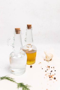 Sarımsak, baharat ve taze dereotlu hafif bir zemin üzerine yerleştirilmiş yağ ve sirke dolu cam şişeler. Kopya alanı ile asgari gıda ve yemek malzemeleri kavramı.