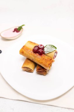 Kiraz dolgulu, taze kiraz ve nane yaprağıyla süslenmiş ev yapımı tatlı krepler. Kopyalama alanı olan en az yiyecek fotoğrafçılığı.