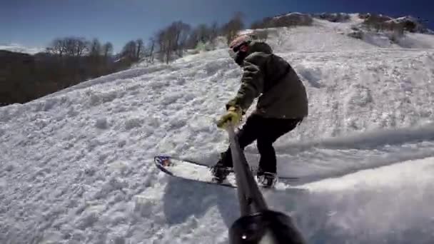 Snowboarder monta na neve fresca, Snowboarder dispara sobre si mesmo enquanto esqui, tempo ensolarado, o sol está brilhando no fundo — Vídeo de Stock