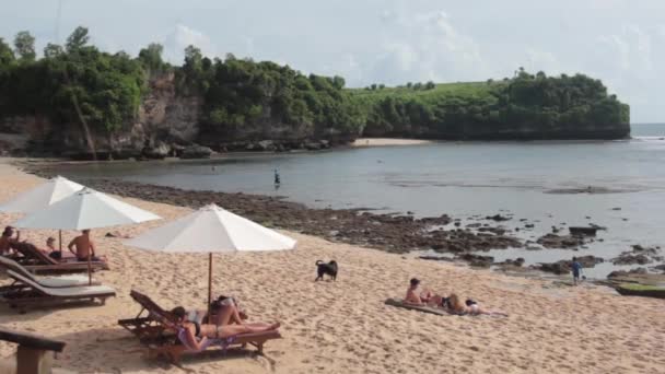 La gente yace en las reposeras del sol en la playa — Vídeos de Stock