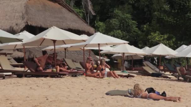 Turister slapper av på Sun Loungers på stranden – stockvideo