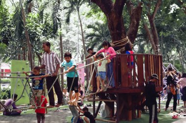 Bir grup çocuk okul tatilinde parktaki ip köprüde oynuyorlar..