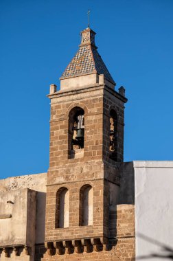 Rota, Cadiz, Spain; 06-10-2025: Bell tower of Nuestra Seora de la O Church in Rota, Cadiz, Spain. Classic Andalusian architecture under clear sky, symbol of faith and heritage