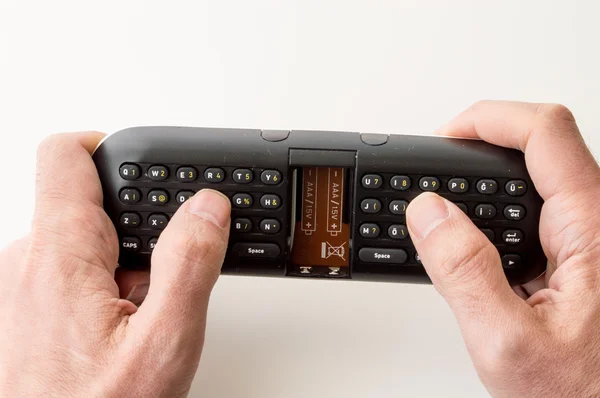 Mãos de homem segurando um teclado de controle remoto — Fotografia de Stock