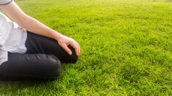 Ung man sitter på grönt gräs i parken — Stockfoto