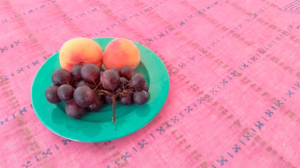 Uvas con albaricoques en una placa — Foto de Stock