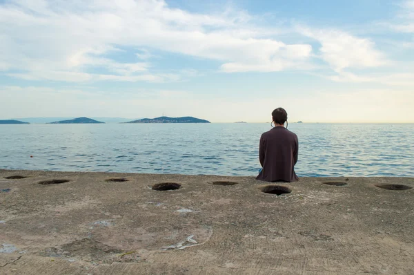 Młody człowiek siedzi nad morzem — Zdjęcie stockowe