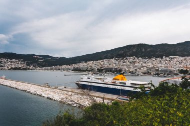 Yunanistan 'ın Kavala limanına demirlemiş büyük bir gemiyle şehir manzarası ve deniz manzarası.