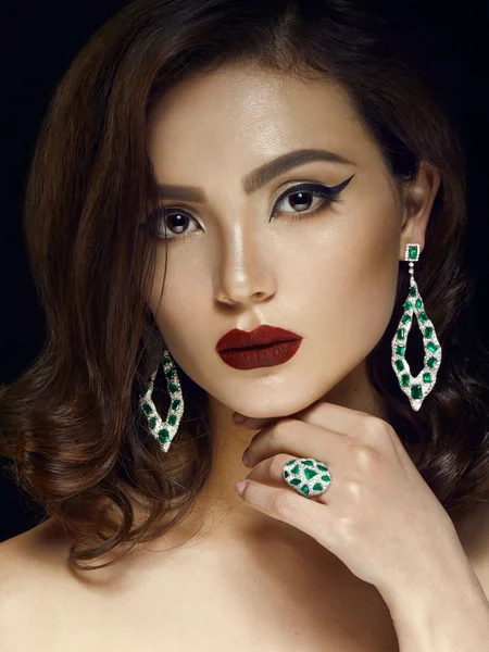 Brunette woman, she is wearing a white gold ring with white diamonds and diamond earrings. emerald jewelry